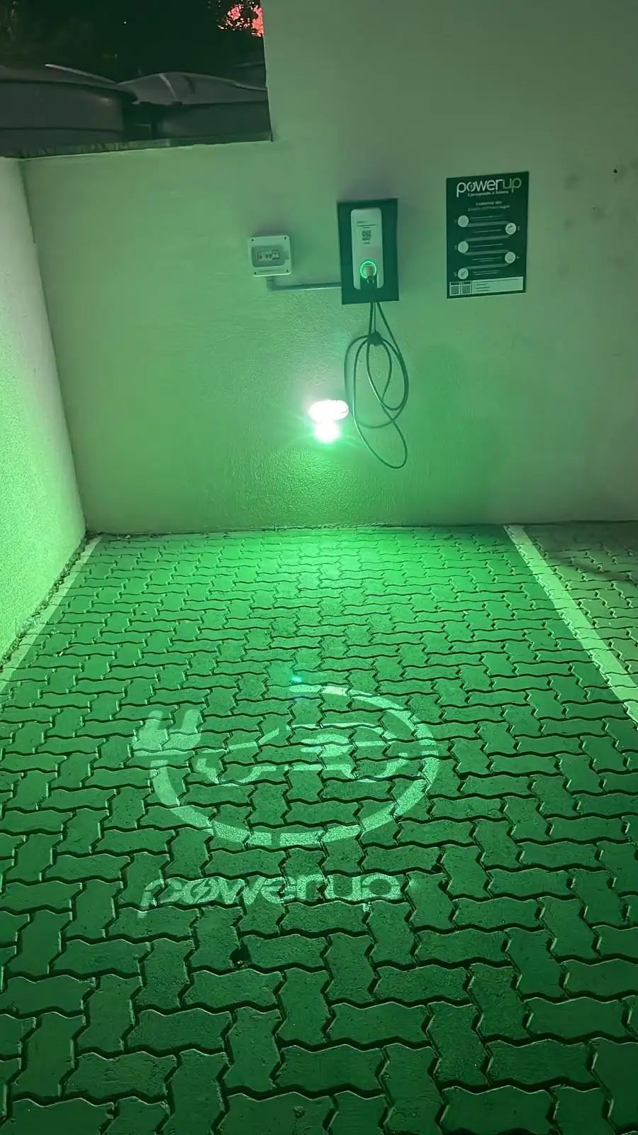Vaga de recarga elétrica PowerUp iluminada à noite em condomínio